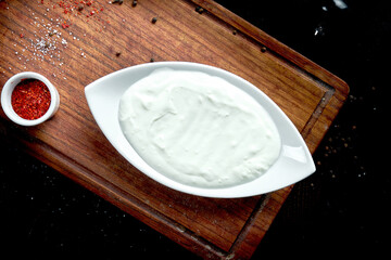 Classic Turkish yogurt in a white plate on a black background.