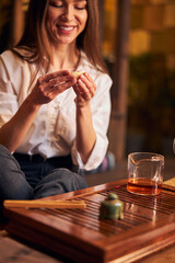 Cheerful young woman enjoying tea ceremony in cafe