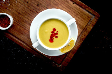 Oriental dish - a yellow lentil cream soup in white on a dark background piala