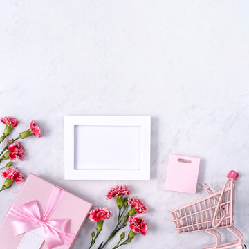 Concept of Mother's day holiday greeting with carnation bouquet on white marble background