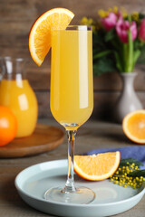 Glass of Mimosa cocktail with garnish on wooden table