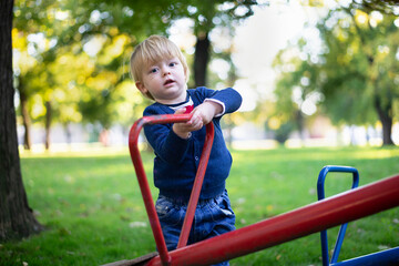 Fototapeta na wymiar Little blue boy of 1 year on the playground