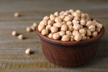 Chickpeas in bowl on wooden table, space for text