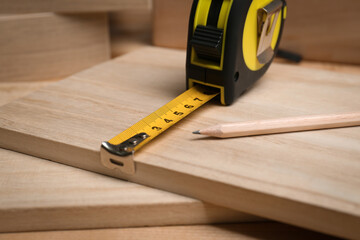 Tape measure and pencil on wooden surface, closeup