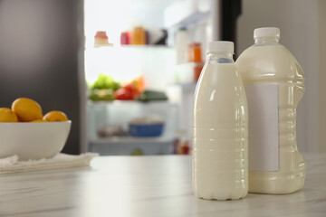 Gallon and bottle of milk on table in kitchen, space for text