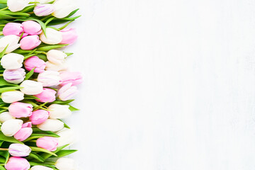 Fototapeta na wymiar Border of pink and white tulips on a light background. Flat lay, copy space