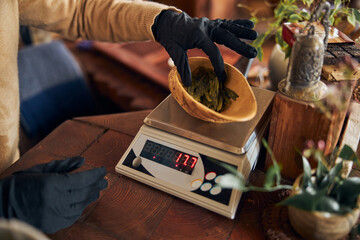 Male worker in black gloves weighing tea leaves