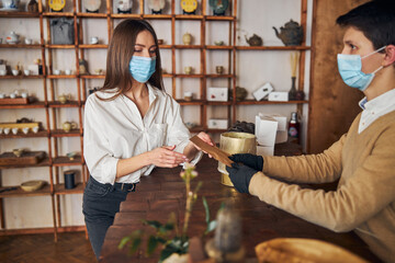 Charming woman in medical mask making purchases in tea shop