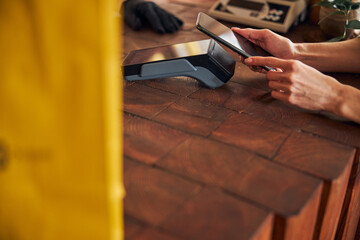Young woman paying for purchases with smartphone