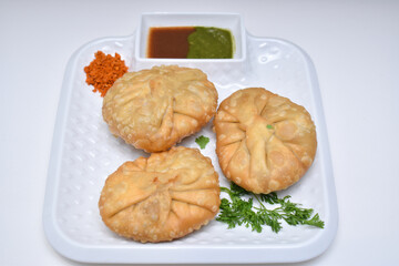 Kachori with dry garlic chutney garnished with coriander leaves kachori is a spicy snack from India also spelled as kachauri and kachodi.Horizontal image with white background and dish