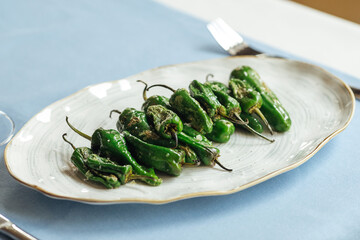 Closeup on cooked hot green spanish padron peppers on a plate