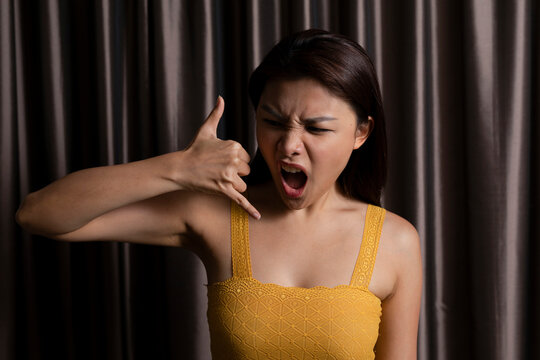 Portrait of a woman in front of a curtain making a call me sign