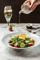 Greek salad of fresh cucumber, tomato, arugula, cream cheese, pine nuts and olives with olive oil. Healthy food, top view