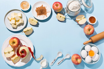 Cooking baking background with ingredients, fresh apples, spices and utensils on blue table.