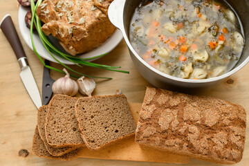 baked meat, soup and blood sausage on a plate, green onion and garlic on wooden background, home...