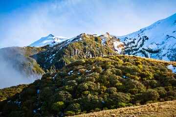 Winter clouds clearing over mountain ridge and snow covered peaks. Egmont National Park, New Zzealand