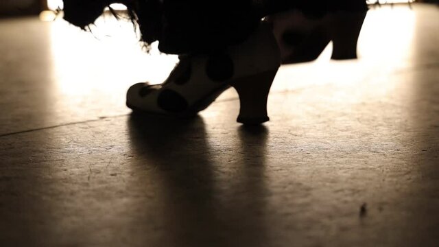 black and white heeled flamenco shoes of a woman dancing flamenco on a illuminated floor