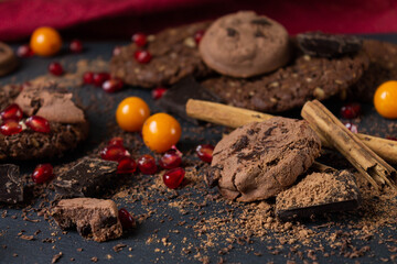 Chocolate cookies, chocolate, cocoa, pomegranate seeds, chocolate chips; physalis berries, kritsa tubes. An idea for the background.
