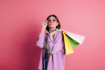 Woman wearing casual sweater on background happy enjoying shopping holding colorful bags wearing summer sunglasses