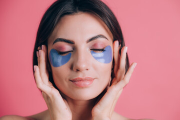 Close-up portrait of a beautiful young woman topless open shoulders with blue collagen pads under her eyes. Beauty concept.