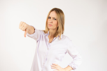 Fototapeta premium Portrait of displeased woman who is showing thumb down over white background.