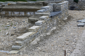 Auf der Baustelle: Bau einer Mauer aus Natursteinen mit integrierter Sitzbank im Rahmen eine...