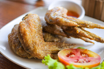 Fried chicken wings in white plate with fresh tomato and lettuce, Selective focus.