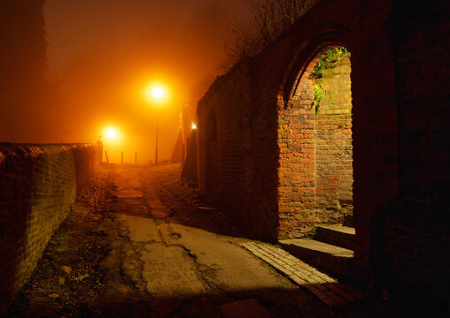 Harrow on the Hill pathway at night with fog and warm streetlights, England 