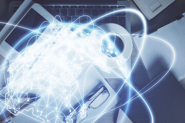 Double exposure of business theme hologram over desktop with phone. Top view. Mobile international...