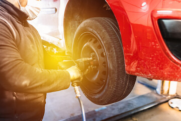 Mechanic changing car wheel in auto repair shop.