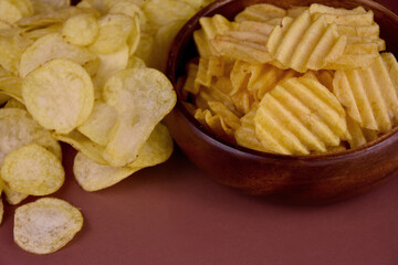 Salty potato chips close-up stock images. Fried potato chips on a brown background stock photo. Salty and spicy potato chips images