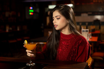 Portrait of a pretty female drinking juice while sitting in a restaurant.