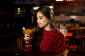 Portrait of a pretty female drinking juice while sitting in a restaurant.