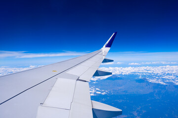 Obraz premium Photo of airplane wing with clouds background, horizon line and clear blue sky