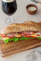 A sandwich of dark bread with salad, bacon, tomatoes and cheese. Breakfast. Fast food.