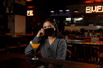 Portrait of a woman wearing face protection mask while sitting in a restaurant.