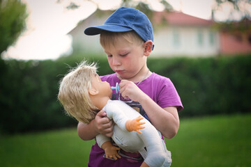 little boy playing with a doll in nature - 418074848