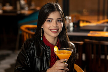 Portrait of a beautiful young Indian girl drinking juice while sitting in a restaurant.