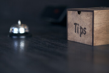 The wooden box for tips and bell for customers, black background with copy space