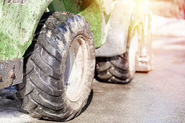 Tractor wheels close up in sunlight. Dirty tractor works. Early spring