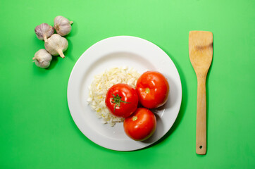 red tomatoes with sliced onions lie on a white plate green background