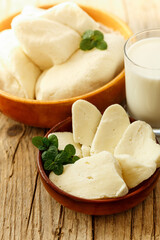 Cypriot semi-hard, fresh homemade unripened brined cheese halloumi in wooden plates and milk. popular in the Levant, Greece and Turkey.Side view in wicker busket on rustic wooden background,close up