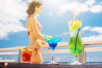 Three summer cocktails on the table with girl on background