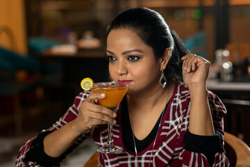Portrait of a pretty female drinking juice while sitting in a restaurant.
