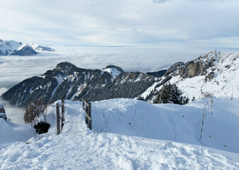 Wooden bridge over a sea of clouds and snowy alpine landscape in Leysin, Switzerland