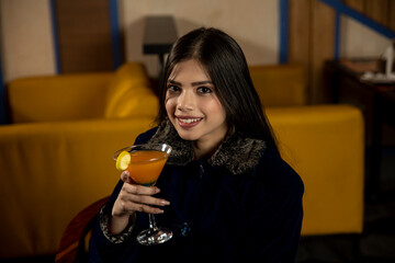 Portrait of a beautiful young Indian girl drinking juice while sitting in a restaurant.