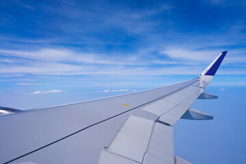 Obraz premium Photo of airplane wing with clouds background, horizon line and clear blue sky