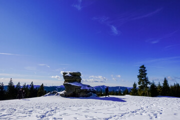 large rock on the top of a mountain with blue sky
