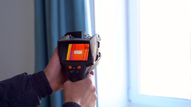 Inspection of a window inside the room with a thermal imager for leaks.