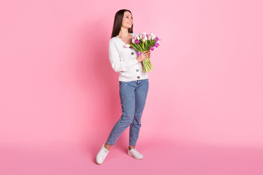 Full length photo of charming sweet attractive young lady look empty space spring holiday flowers isolated on pink color background